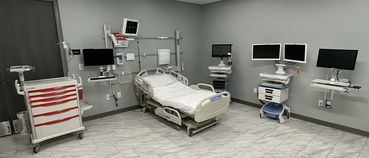 Technician installing ceiling-mounted medical equipment in a hospital room